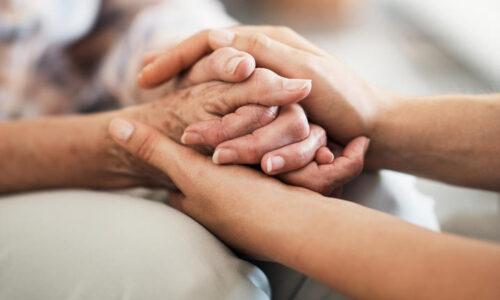 Cropped shot of an unidentifiable nurse consoling her elderly patient by holding her hands at home